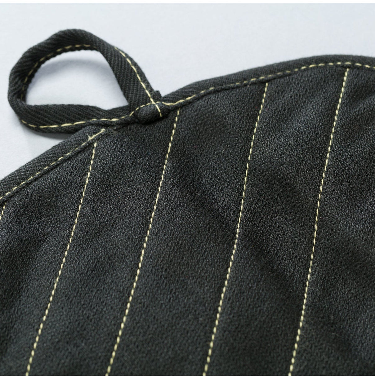 Black oven mitt with white stitching on a light gray background